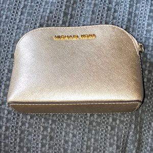 A Gold Michael Kors small accessory purse.